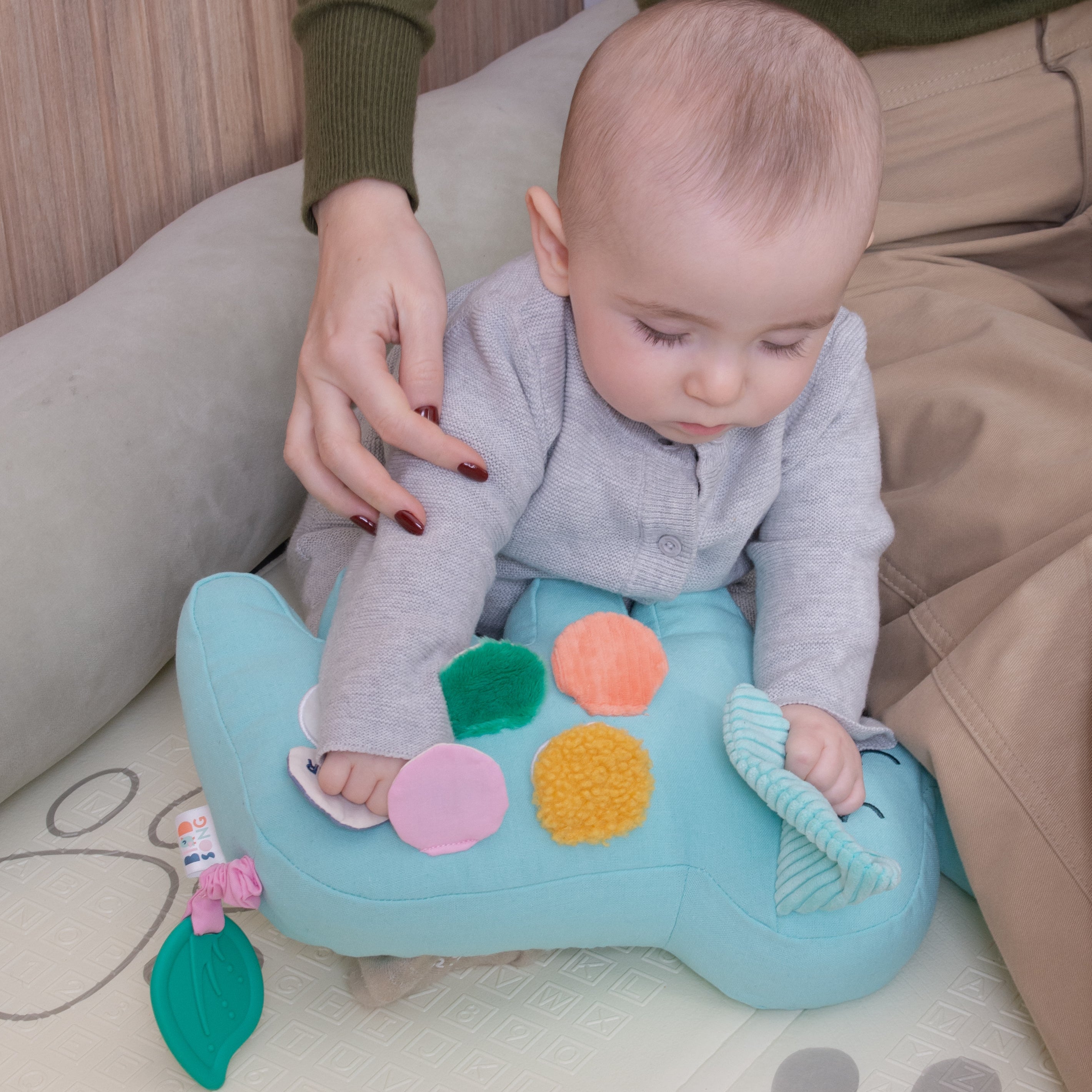 A baby is holding Birdsong's elephant bilingual toy while his mom gently holds him.