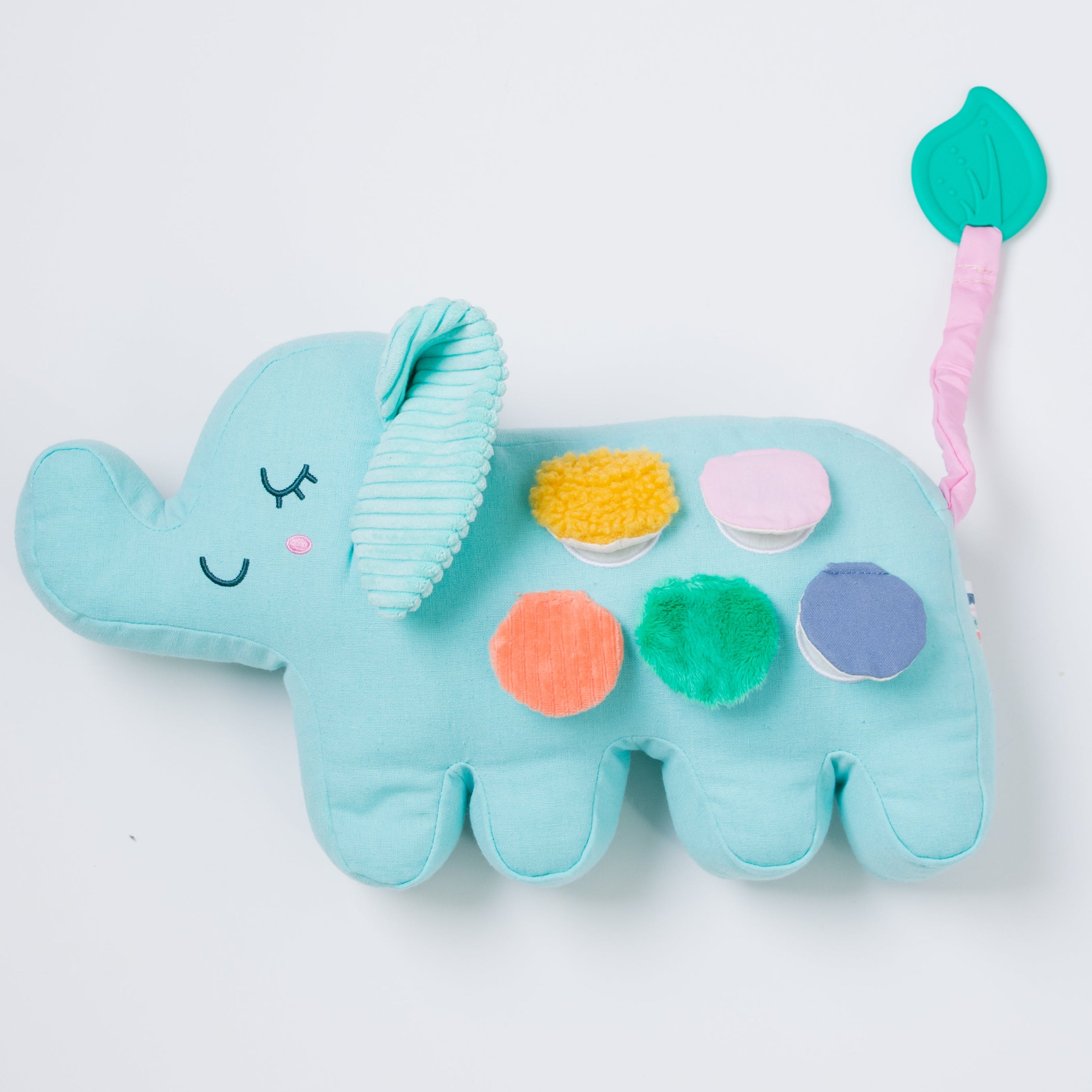 A light blue plush elephant baby toy with textured fabric panels and colorful circular buttons, shown on a plain white background.